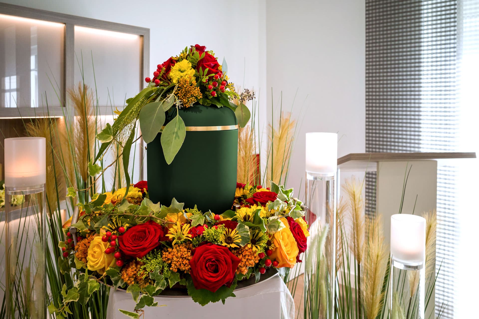 Grüne Urne mit Blumenschmuck bei einer Feuerbestattung, Kuhn Bestattungen Asperg.