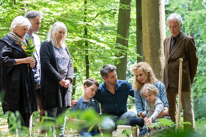 Familie bei einer FriedWald-Bestattung, die Abschied von einem geliebten Menschen nimmt.