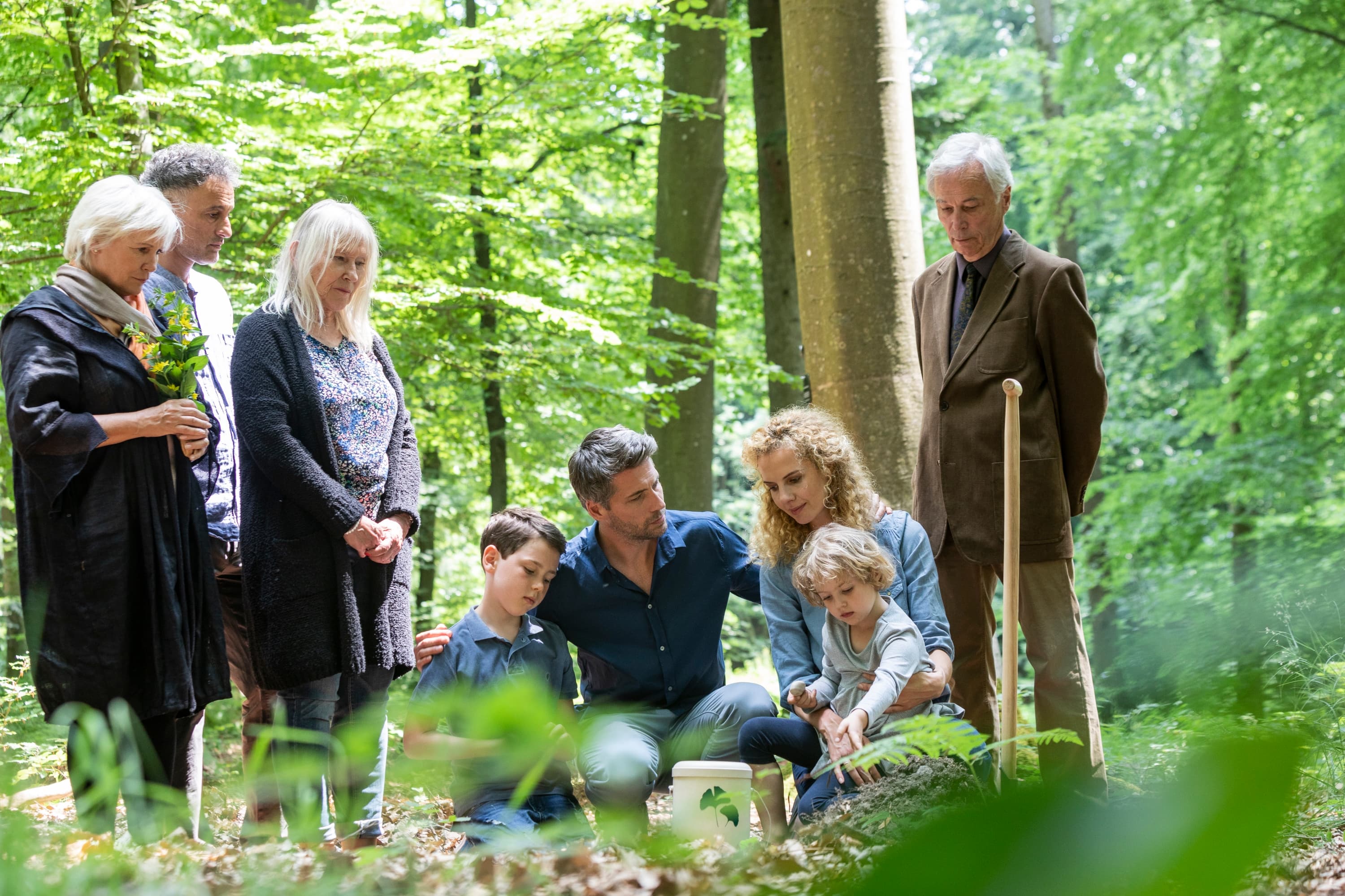 Familie bei einer FriedWald-Bestattung, die Abschied von einem geliebten Menschen nimmt.