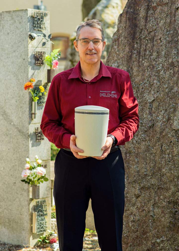 Geschäftsführer Michael Großhaupt mit Urne am Friedhof – Kuhn Bestattungen Asperg