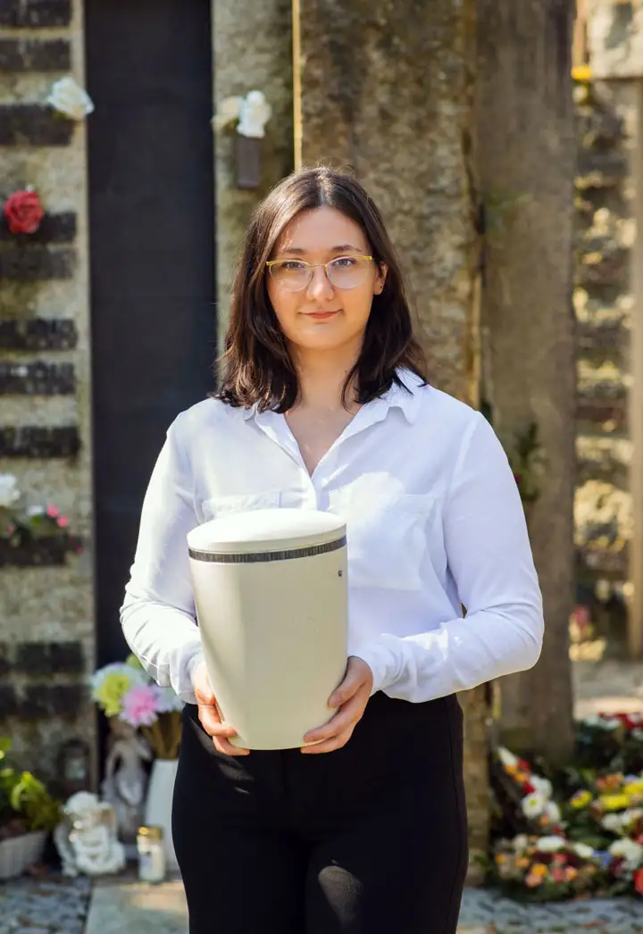 Einfühlsame Urnenbestattung mit Kuhn Bestattungen Despina Theodoru von Kuhnbestattungen Asperg hält eine Urne auf dem Friedhof