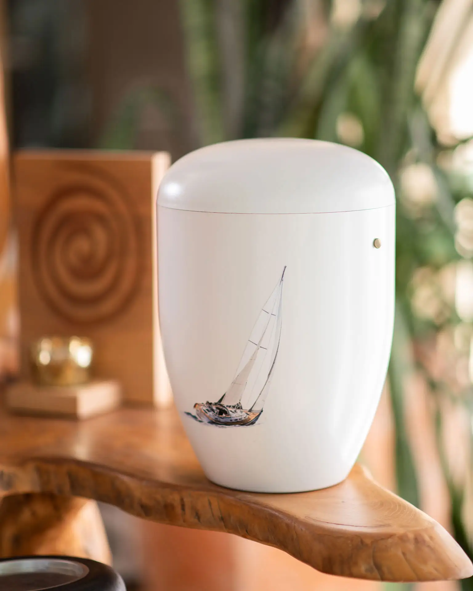 Seebestattung – Würdevolle Beisetzung auf See bei Kuhn Bestattungen Weiße Urne mit einem handgemalten Segelboot-Motiv, vorbereitet für eine Seebestattung durch Kuhn Bestattungen.