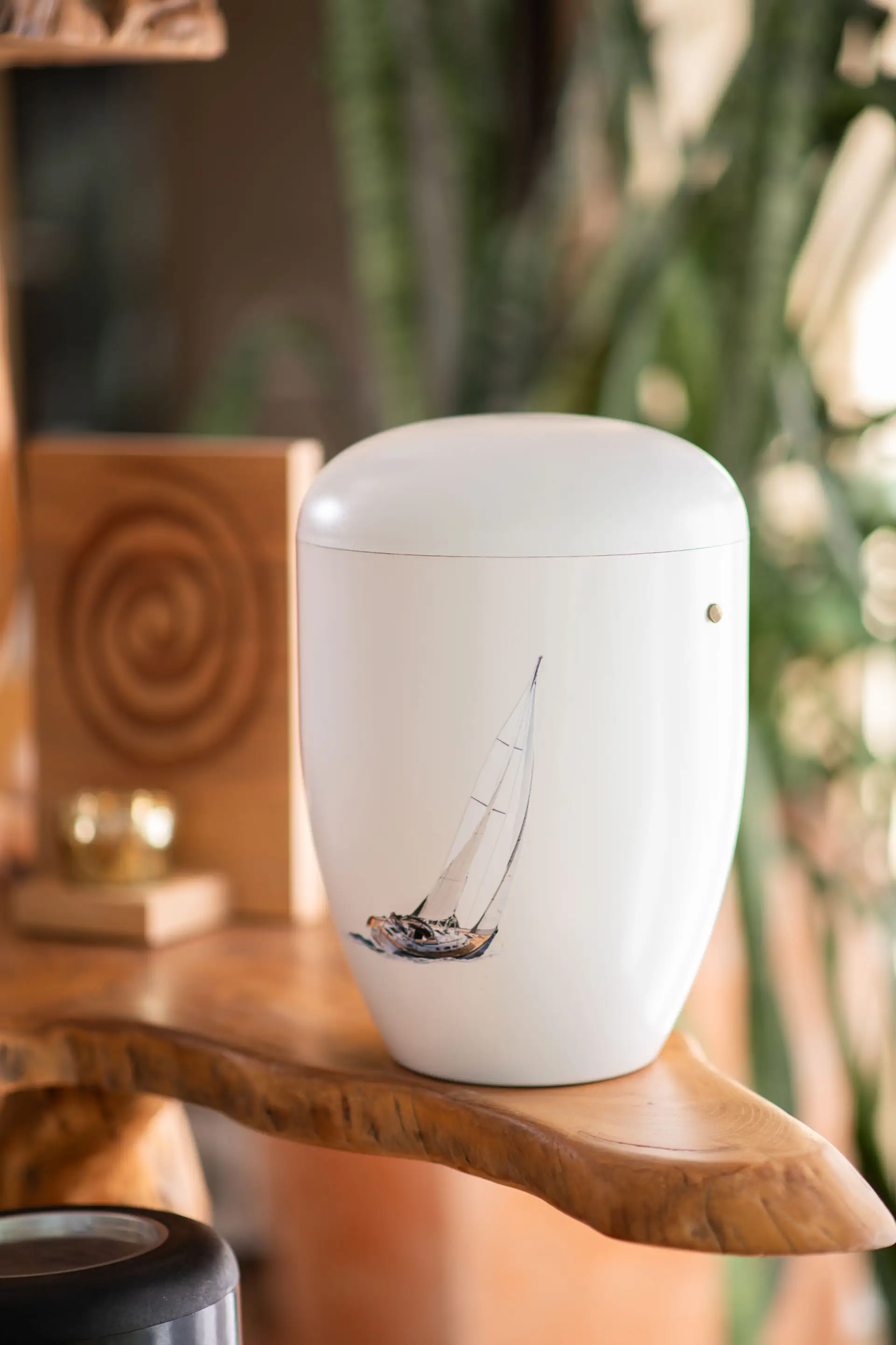Seebestattung – Würdevolle Beisetzung auf See bei Kuhn Bestattungen Weiße Urne mit einem handgemalten Segelboot-Motiv, vorbereitet für eine Seebestattung. Naturverbundene und würdevolle Abschiednahme auf See durch Kuhn Bestattungen in Asperg.